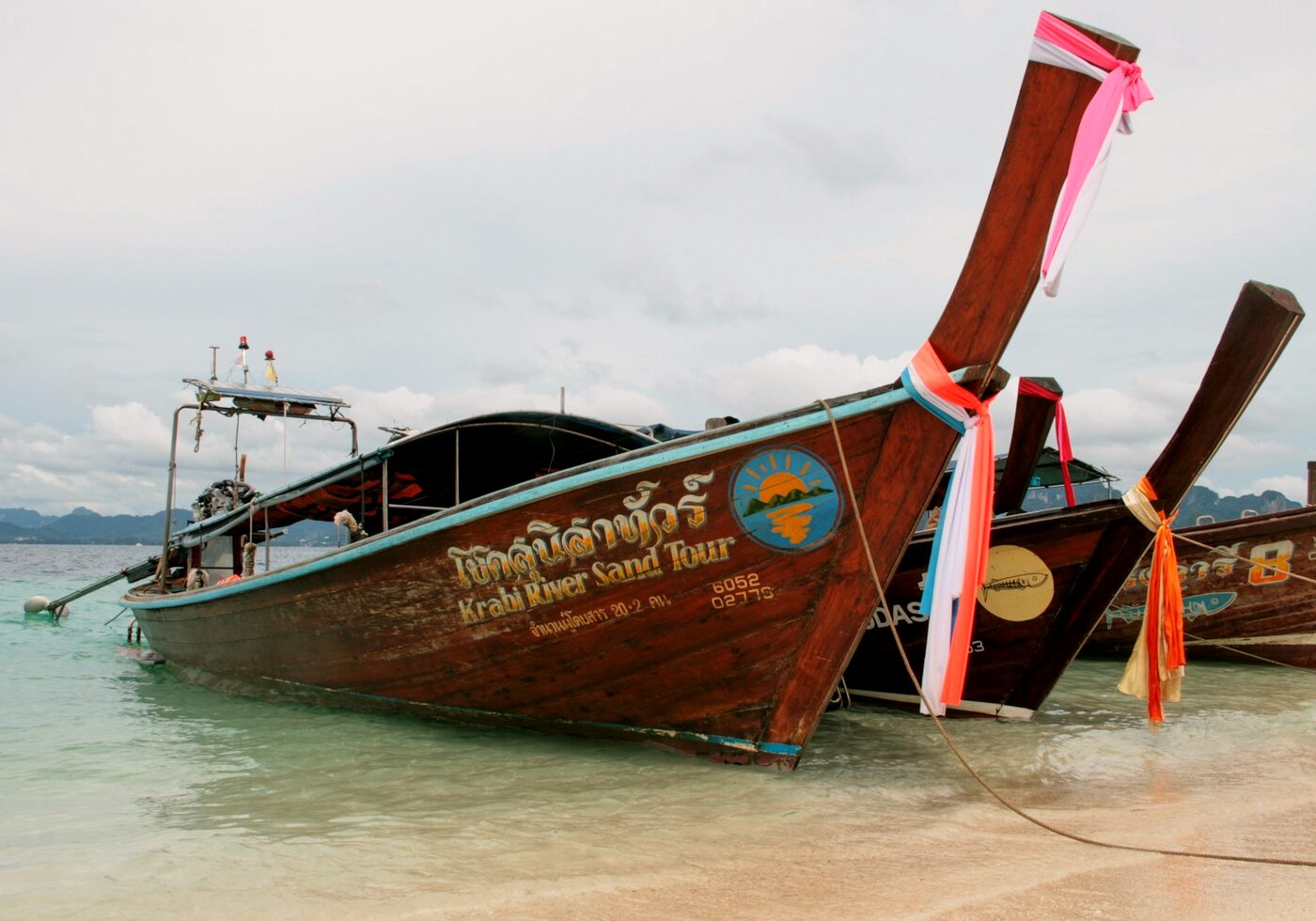 A traditional Thai longtail boat moored on a white-sand beach