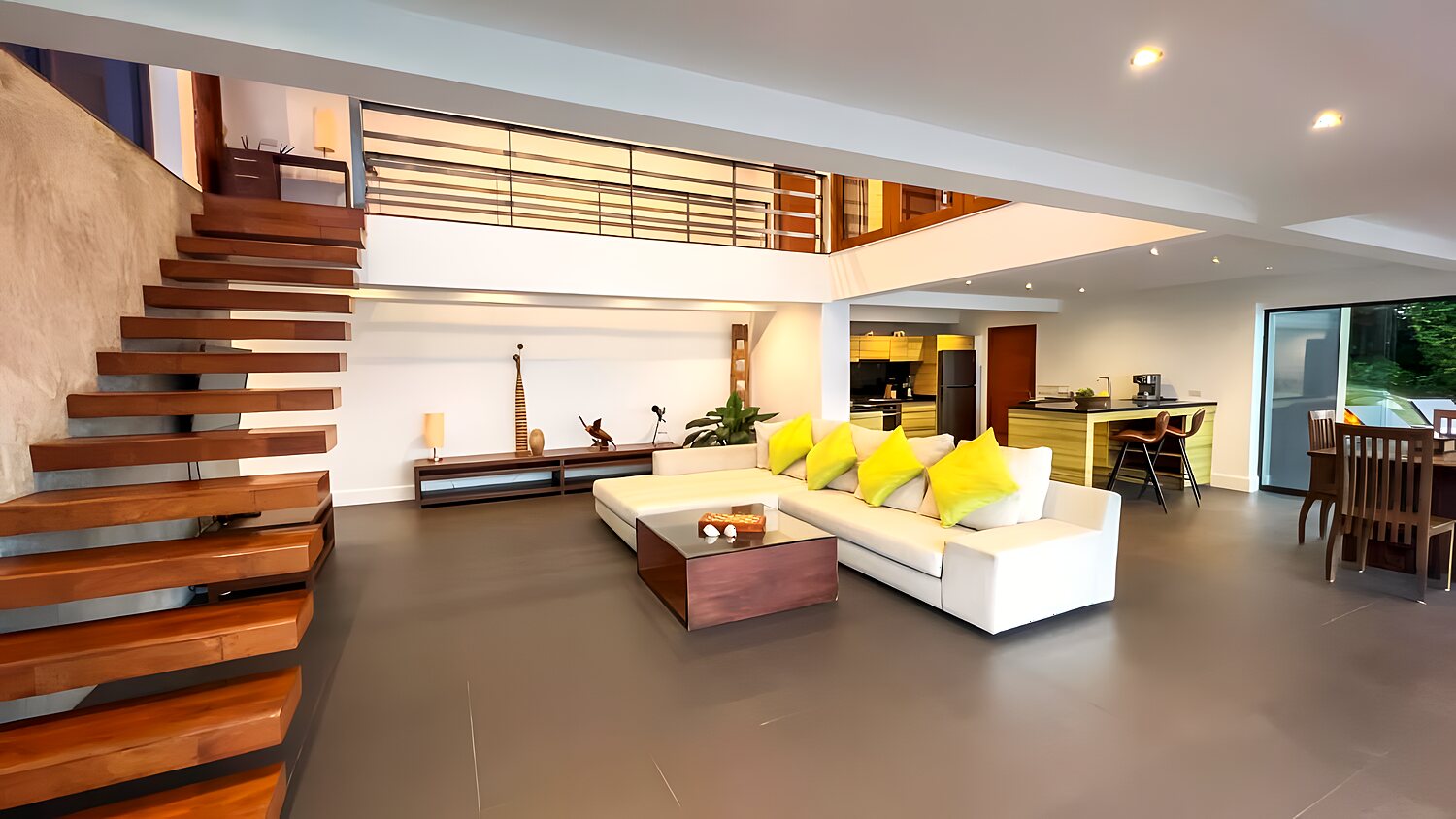 The open-plan living room with a floating staircase and sea view through full-height glass